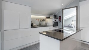 A modern kitchen with white cabinetry, a central island, and a microwave above the oven.