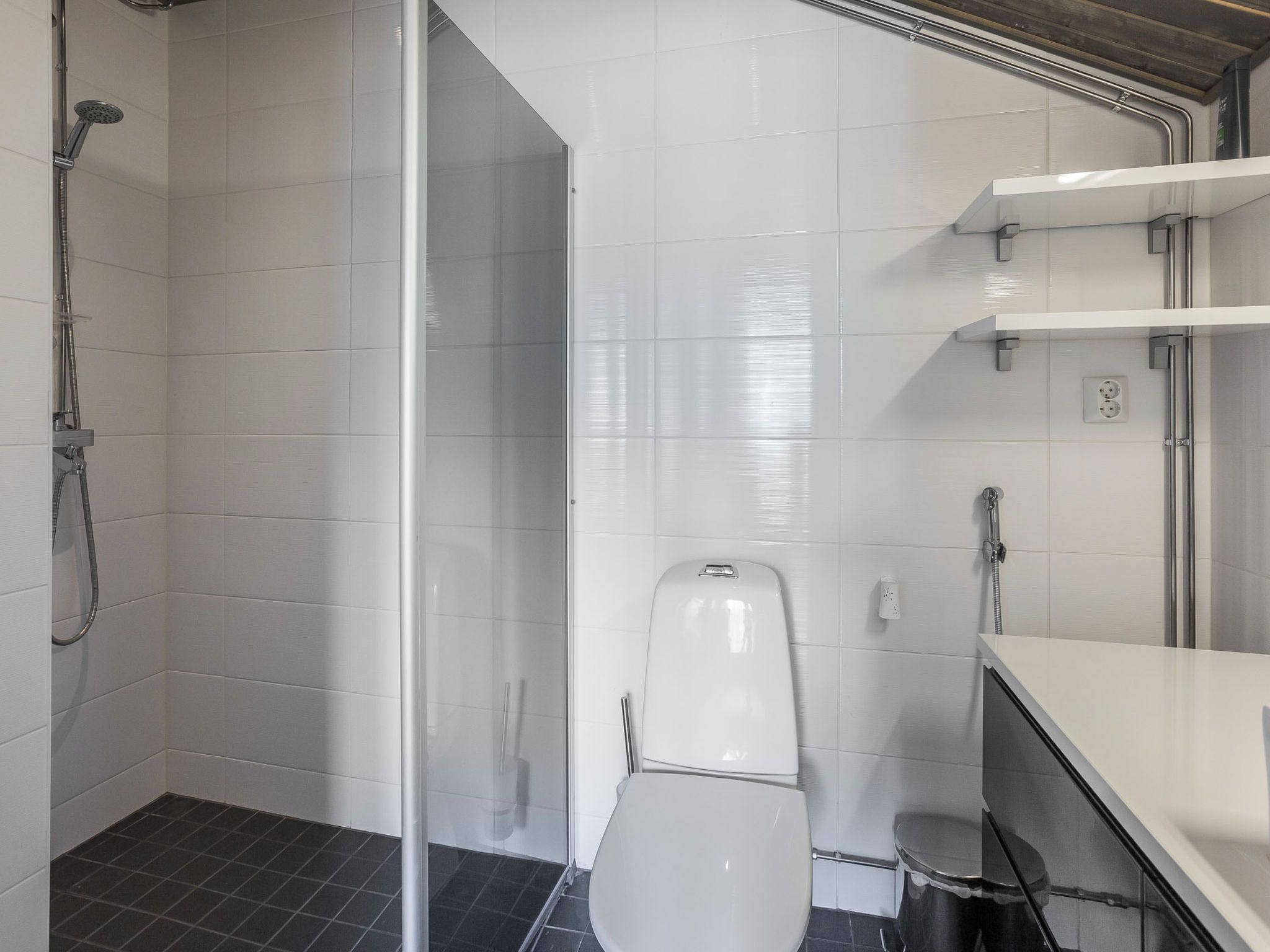 Un bagno moderno con box doccia in vetro, un water e un lavandino con specchio.