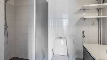 Un bagno moderno con box doccia in vetro, un water e un lavandino con specchio.