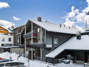 Ein mehrstöckiges Gebäude mit Balkonen, einem mit Schnee bedeckten Dach und einem Schild, das einen Ort angibt.