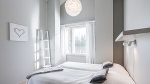 A bedroom with two beds, a ladder, a chandelier, and a window with curtains.