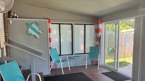 Un patio techado con dos sillones turquesa, una mesita y un ventilador.