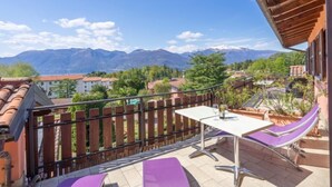 A balcony with a table and chairs, overlooking a mountainous landscape.