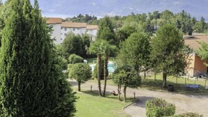 A hotel with a pool, surrounded by trees and mountains in the background.