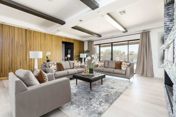 A modern living room with a sectional sofa, a coffee table, and a fireplace.