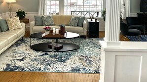 Un salon avec un canapé, une table basse et une grande fenêtre avec des rideaux.