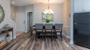 A dining area with a wooden floor, a chandelier, a painting, and a refrigerator. - Gorgeous Clean 3 Bdrm, 2 Owner Suites, South Forest Beach, near beach and pool! (Hilton Head Island)