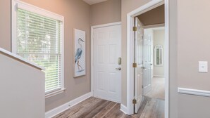 A hallway with a wooden floor, a white door, and a framed picture on the wall. - Gorgeous Clean 3 Bdrm, 2 Owner Suites, South Forest Beach, near beach and pool! (Hilton Head Island)