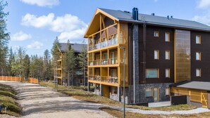 A modern multi-story building with balconies, a gravel driveway, and a forested area in the background. - Tunturinlaita b3 by Interhome (Kittilä)