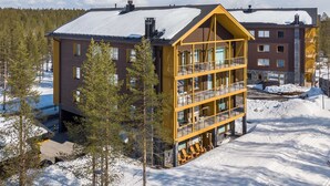 A multi-story lodge with a prominent yellow facade, large windows, and a balcony area. - Tunturinlaita b3 by Interhome (Kittilä)