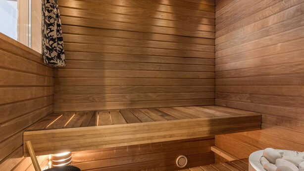 A sauna with wooden benches, a bucket, and a stone basin. - Tunturinlaita b3 by Interhome (Kittilä)