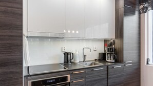 A modern kitchen with dark wood cabinets, stainless steel appliances, and a black countertop. - Tunturinlaita b3 by Interhome (Kittilä)