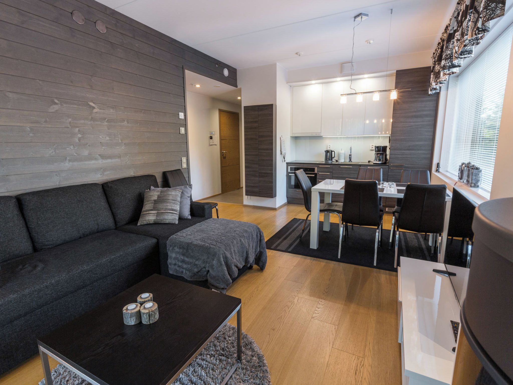 A modern living room with a sofa, coffee table, and a dining area with chairs and a table.