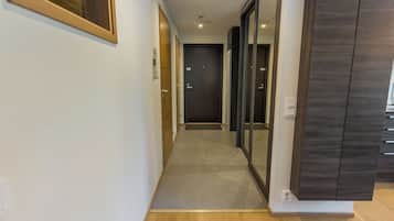A hallway with a wooden floor, a door at the end, and a wall-mounted cabinet.