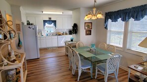 Uma cozinha com armários brancos, uma mesa de jantar com cadeiras e um candelabro.