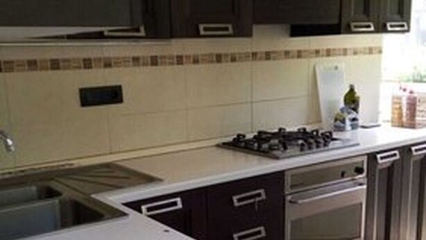 A kitchen with dark cabinets, a gas stove, a sink, and a tiled backsplash. - Delizioso Appartamento con Giardino a Pochi Metri dal Mare/centro (Aci Castello)