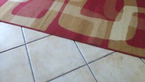 A red sofa against a beige wall with a patterned rug on a tiled floor. - Delizioso Appartamento con Giardino a Pochi Metri dal Mare/centro (Aci Castello)