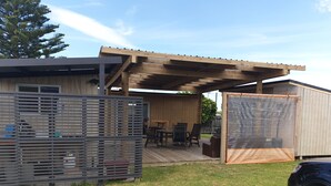 A covered outdoor area with a wooden deck, a grill, and a screened porch. - Perfect in Pataua (Pataua North)