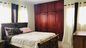 Un dormitorio con una cama de madera, un armario y una cómoda.