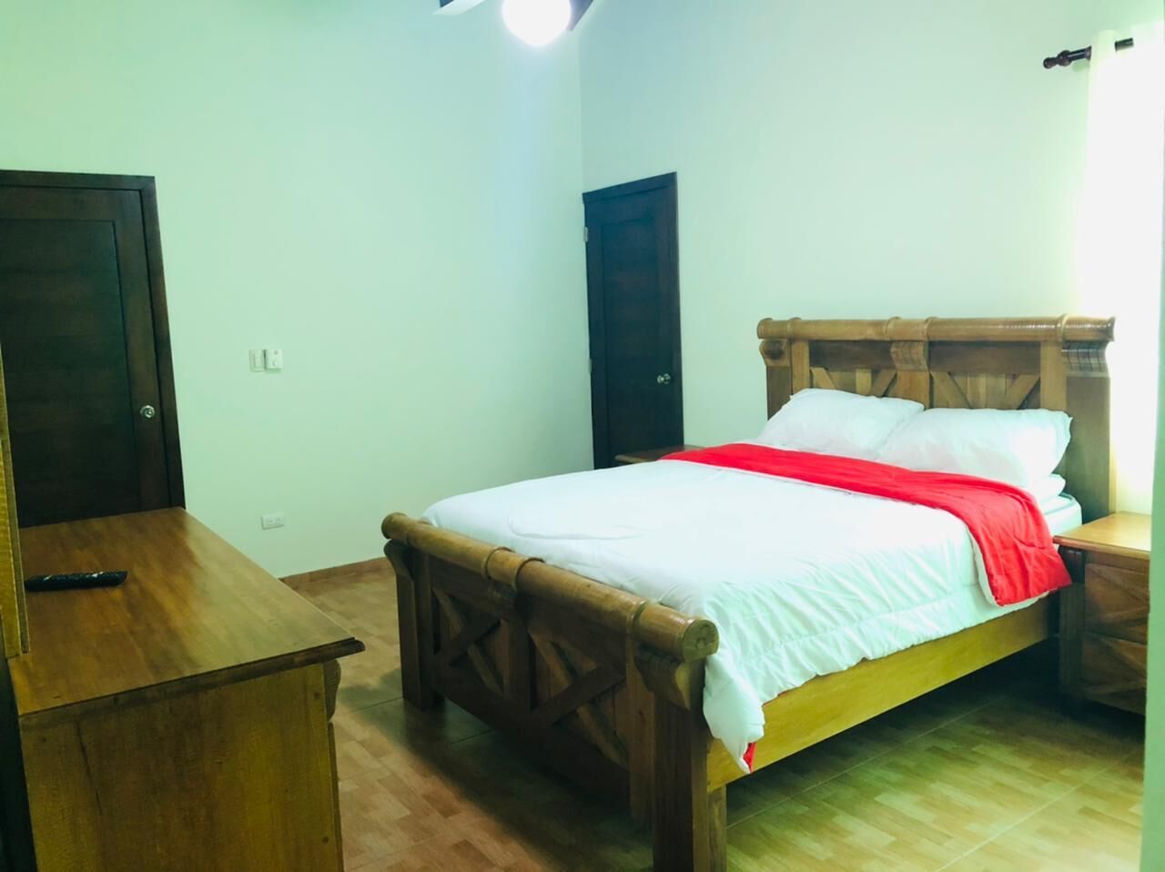 Une chambre à coucher avec un lit en bois, une table de chevet, une armoire et une porte.