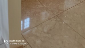 A kitchen with wooden cabinets, a stainless steel refrigerator, and a tiled floor. - Lagoon Residence Appt Bioguera (Porto-Novo)