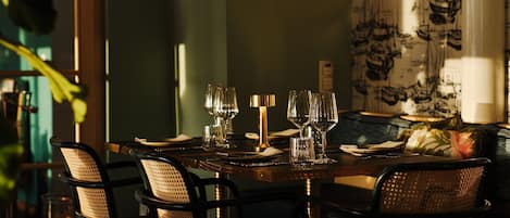 A dining table set for six with chairs, a lamp, and a patterned wallpaper.