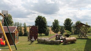 Une aire de jeux avec un mur d’escalade, des balançoires et un toboggan en forme de tronc d’arbre.