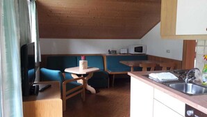 Una kitchenette compacta con microondas, un lavamanos y una pequeña zona de comedor con sillas y una mesa.