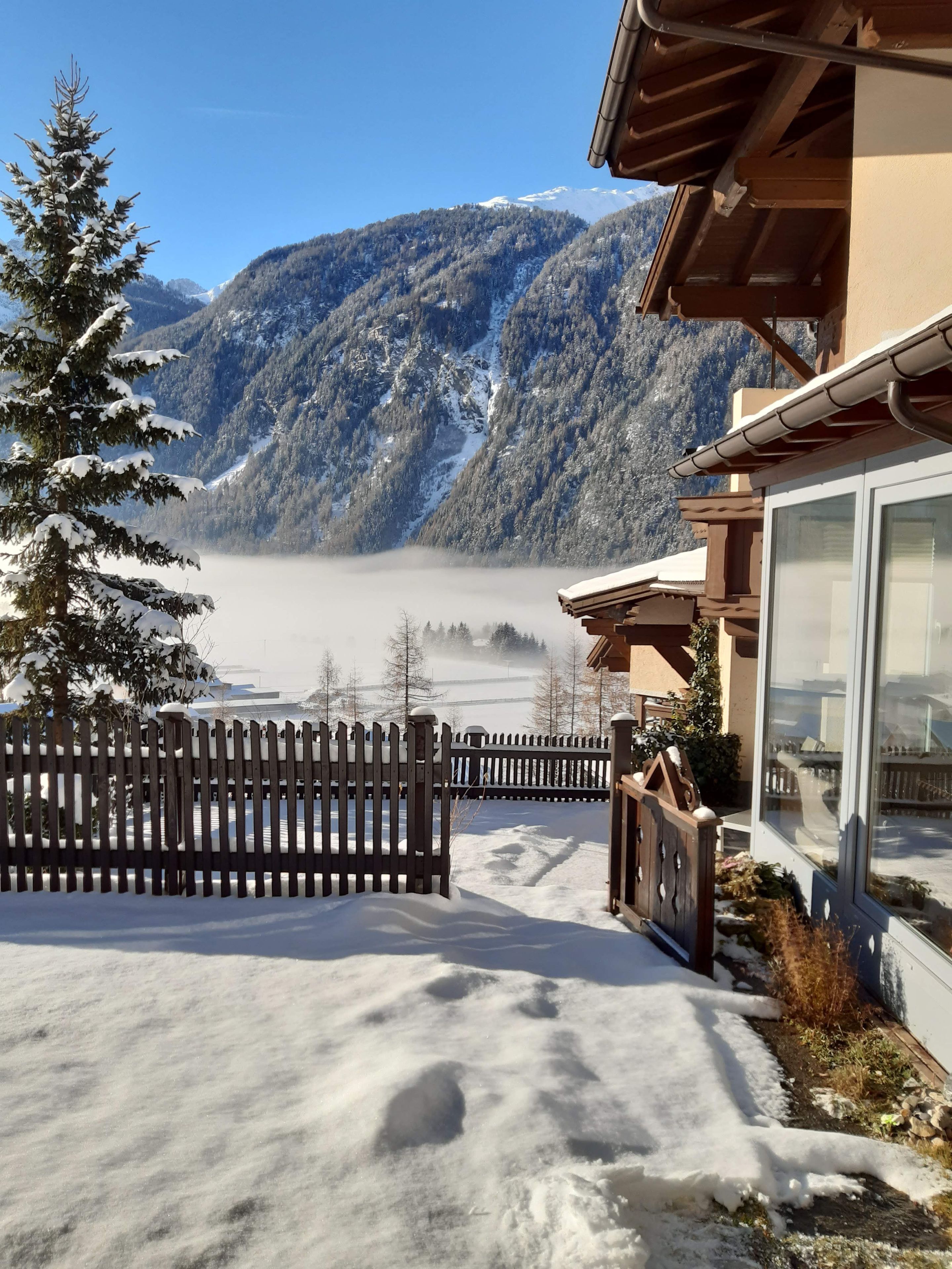 A mountain view with a wooden fence and a building with large windows.