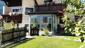 Een chalet met een houten balkon, een glazen deur en een omheinde tuin.
