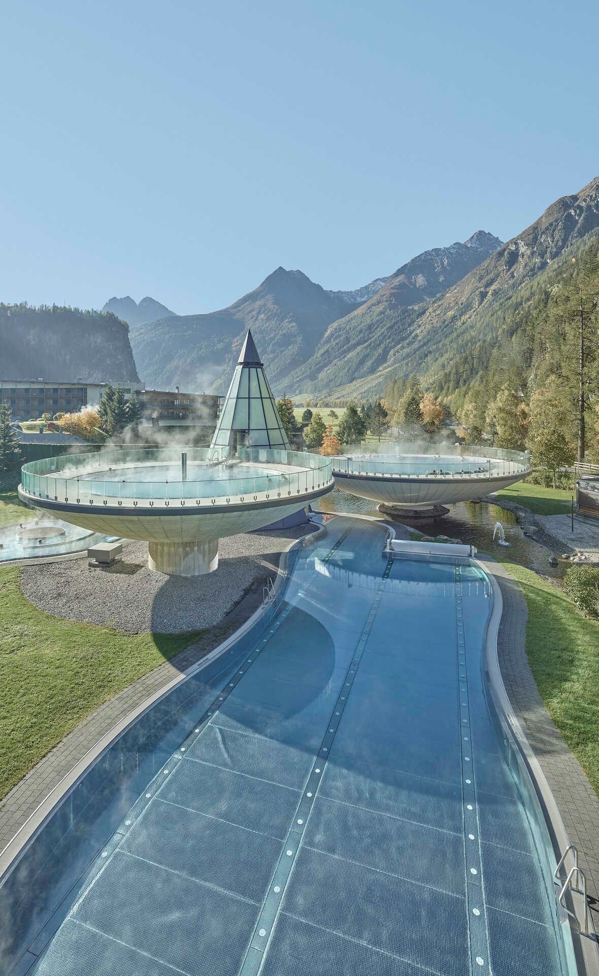 Un spa moderne doté d’un élément aquatique central, entouré d’une promenade circulaire et d’une plateforme d’observation.