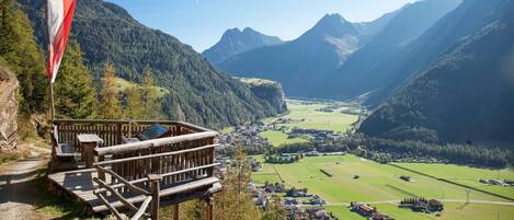Blick auf Berge mit einer Holzdielen-Terrasse, einer Flagge und einem Tal darunter.