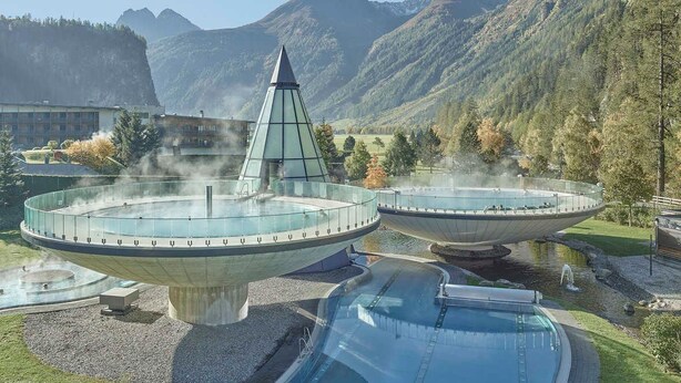 Een moderne spa met een centraal waterpartij, omringd door een rondgangpad en een uitkijkplatform.