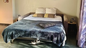 Un dormitorio con una cama, un espejo en la pared y una mesita de noche con lámpara.
