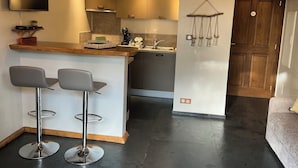 Una cocina moderna con barra, televisor montado en la pared y techo de madera.