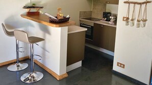 Cocina compacta con barra, televisor y refrigerador con una lámpara original.