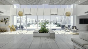 A spacious lobby with a large window offering a city view, a central planter with greenery, and a modern seating area. - Tanoak Resort (Ataqah)