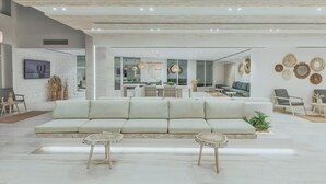 A spacious living area with a large sofa, two side tables, and a dining area with a table and chairs. - Tanoak Resort (Ataqah)