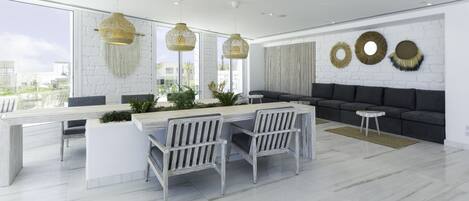 Una sala moderna con un sofá blanco, un comedor con una mesa y sillas blancas, y decoración en la pared.