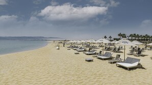 A beach with sun loungers and umbrellas, a clear sky, and a calm sea. - Tanoak Resort (Ataqah)
