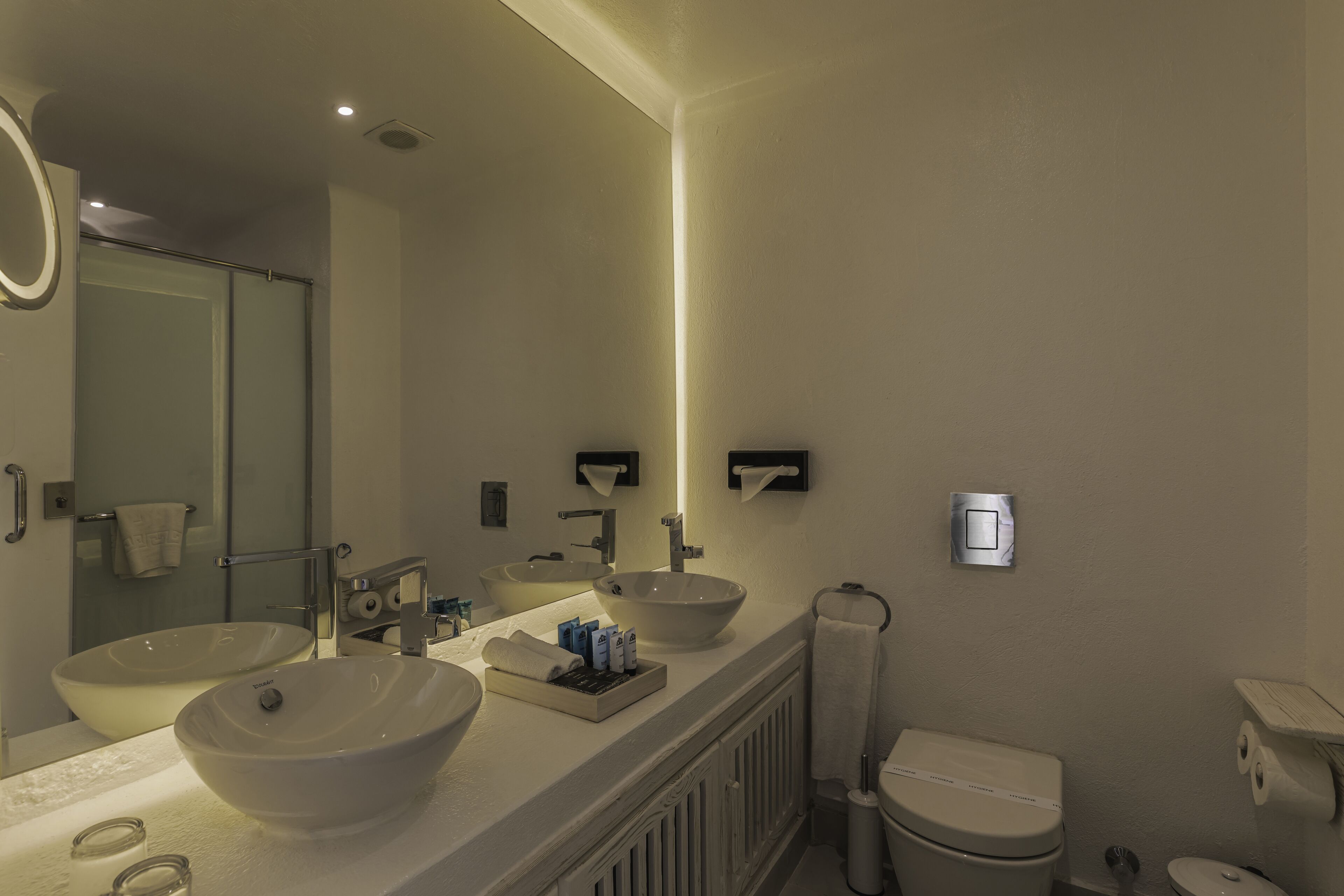 Une salle de bain moderne avec deux lavabos, un miroir et des toilettes.