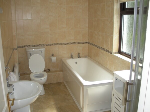 Une salle de bain avec des toilettes, un lavabo et une baignoire.