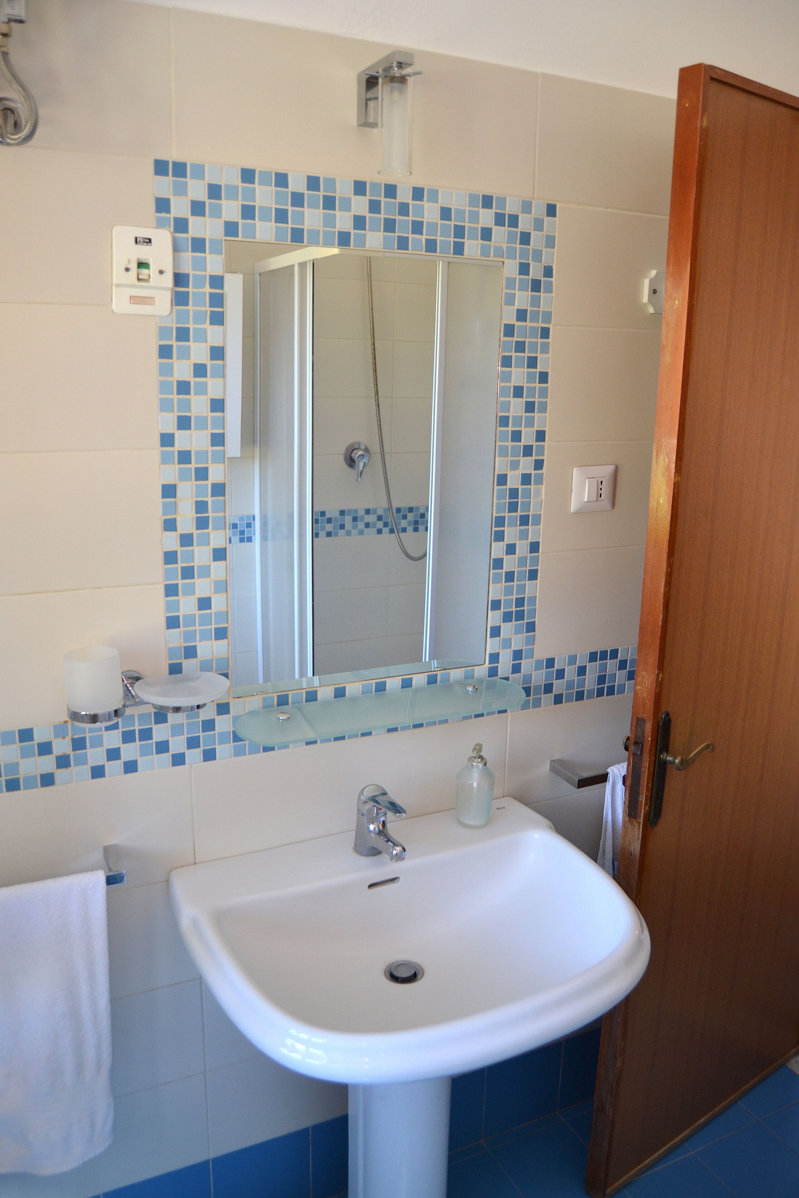 A bathroom with a white sink, a mirror, and a shower.
