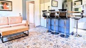Un interior moderno con un sofá, piso estampado y una zona de bar con taburetes.
