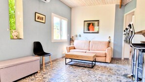 Una sala de estar con un sofá, un sillón, una mesa de centro, un banco y un suelo estampado.
