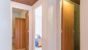 A hallway with wooden doors leading to a bedroom with a bed and a bathroom with a tiled shower. - Beautiful 3-room apartment for 7 with balcony, Montgenèvre (Montgenèvre)