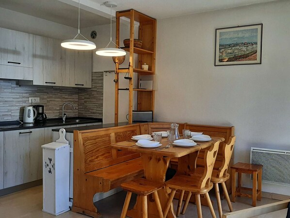 A modern kitchen with wooden cabinetry, a dining table set for four, and pendant lighting. - Beautiful 3-room apartment for 7 with balcony, Montgenèvre (Montgenèvre)