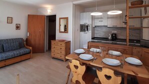 A compact living space with a kitchenette, a dining area with heart-shaped chairs, a sofa, and a wooden cabinet. - Beautiful 3-room apartment for 7 with balcony, Montgenèvre (Montgenèvre)