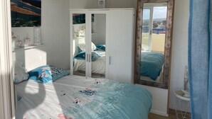 A bedroom with a bed, a wardrobe, a mirror, and a window. - Appart: T3 Front DE MER -orienté SUD - Terrasse 22 M2-2 Piscines- Parking (lacanau océan)