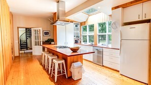 Uma cozinha moderna com uma ilha central, banquetas, máquina de lavar louça e frigorífico.